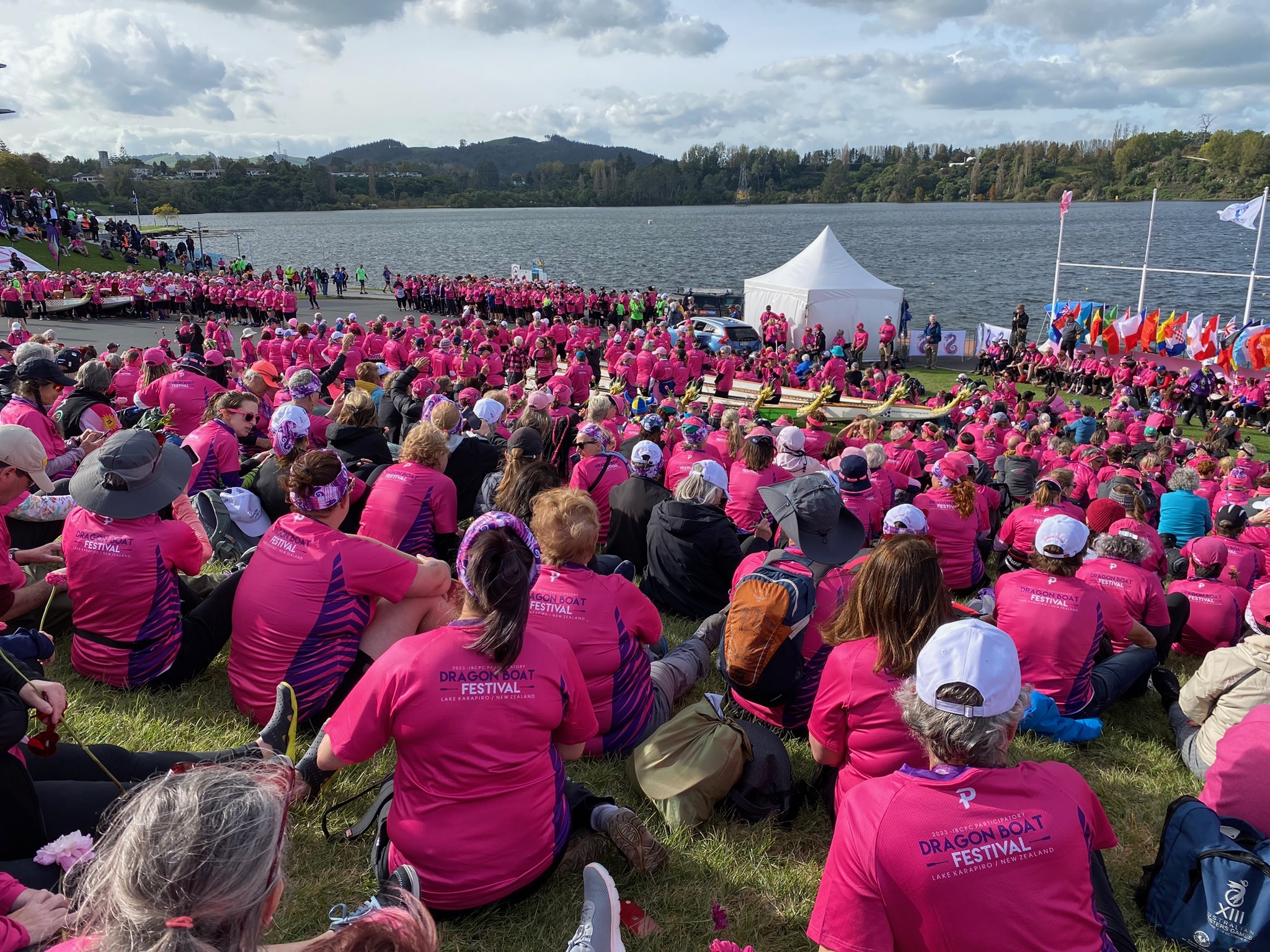 Image of a dragon boat festival "flower ceremony" to honor those with breast cancer, and a map from Boston to New Zealand where the 2022 festival is located